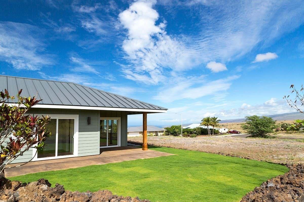 Side lawn and covered entry of a new Waikoloa Village home
